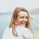 Woman smiling over her shoulder with a blurred natural background.