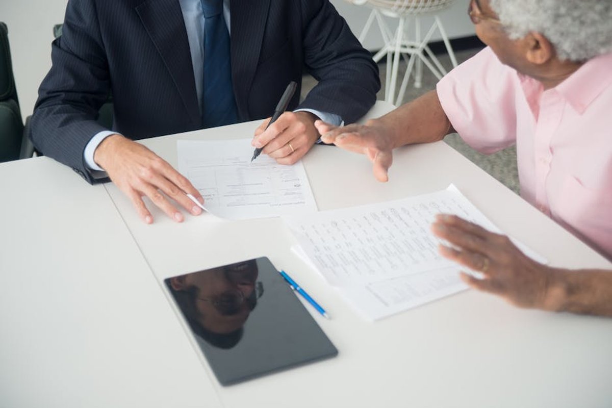 Business consultant meeting with elderly client discussing aged care advisory services and documents