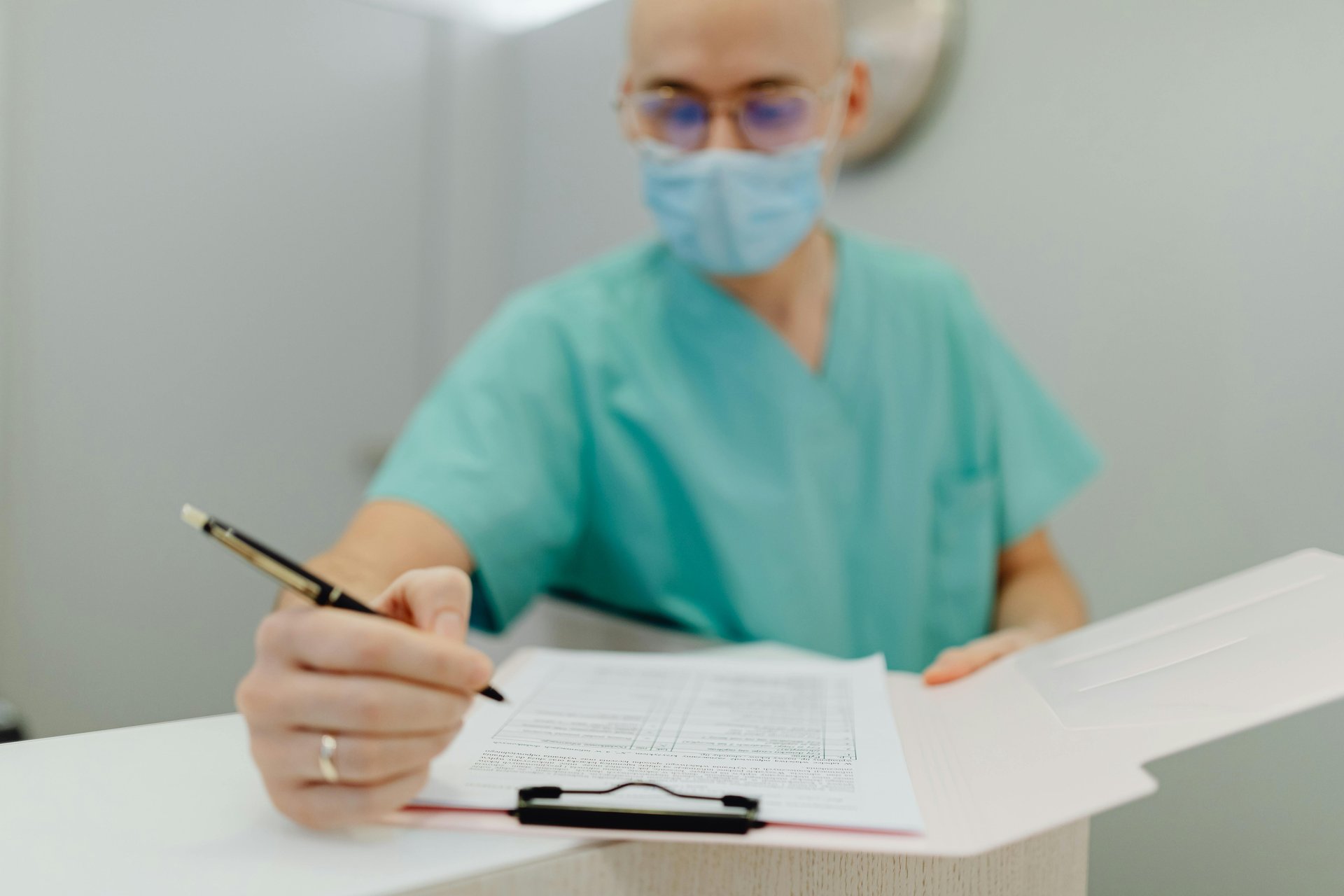 Nurse wearing mask writing patient notes on clipboard as part of aged care documentation system