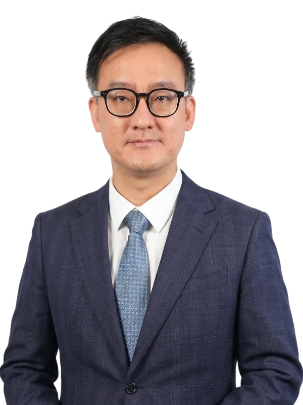 Fei Teng wearing glasses and a dark blue suit with a light blue tie stands facing the camera with a neutral expression.