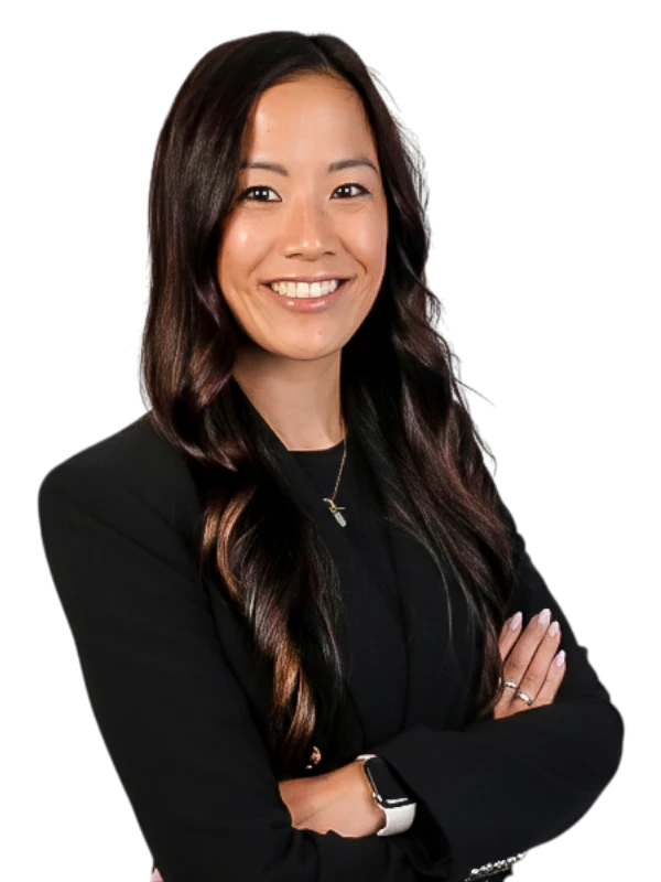 Stephanie Ng wearing a black blazer stands with arms crossed, smiling at the camera against a plain background.