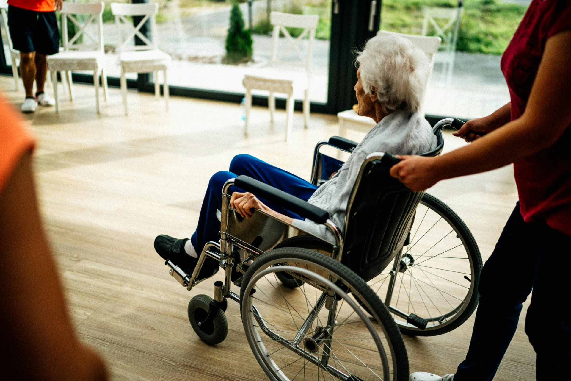 Caregiver assisting senior adult in wheelchair at an aged care facility demonstrating quality care standards