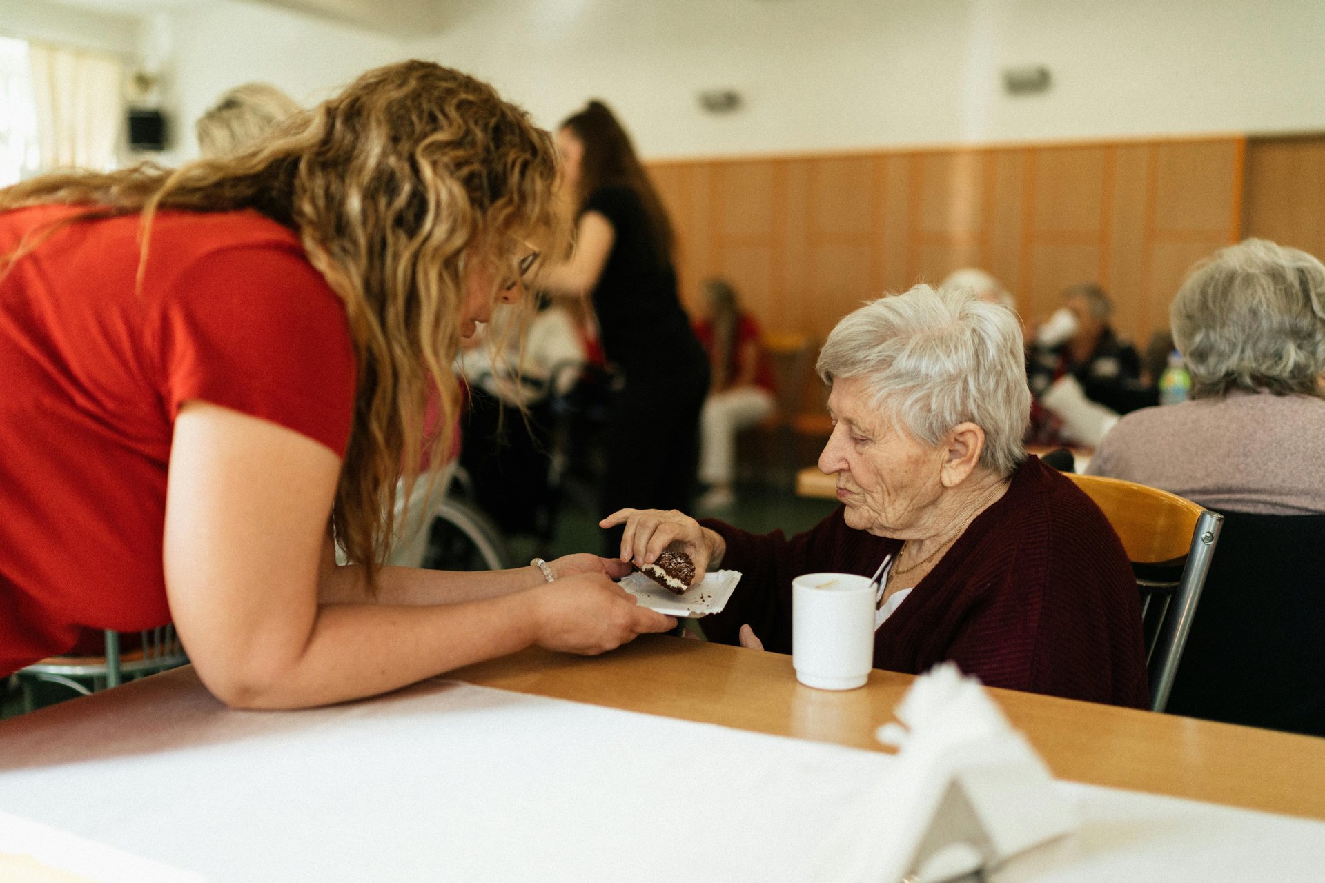 Caregiver assisting elderly woman in an aged care nursing home facility