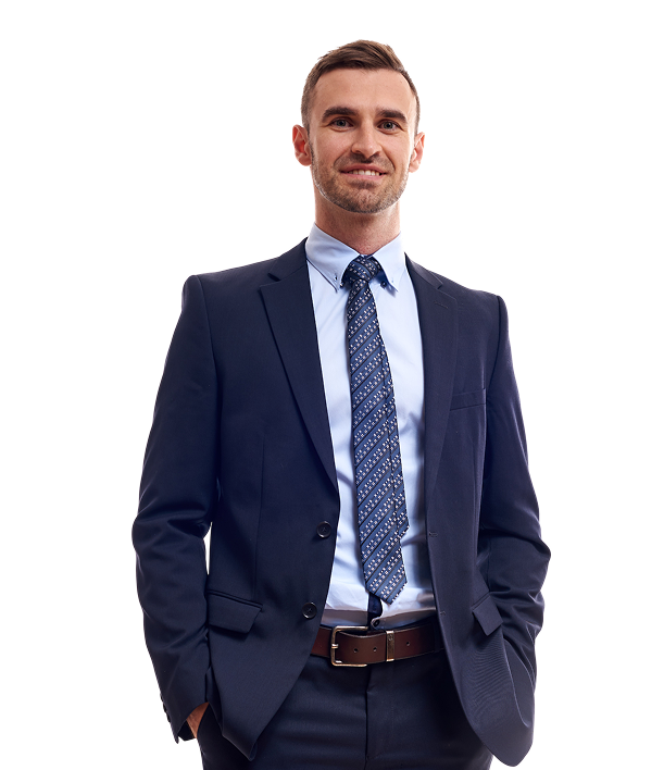 A man in a navy blue suit and patterned tie stands with hands in his pockets against a plain white background.