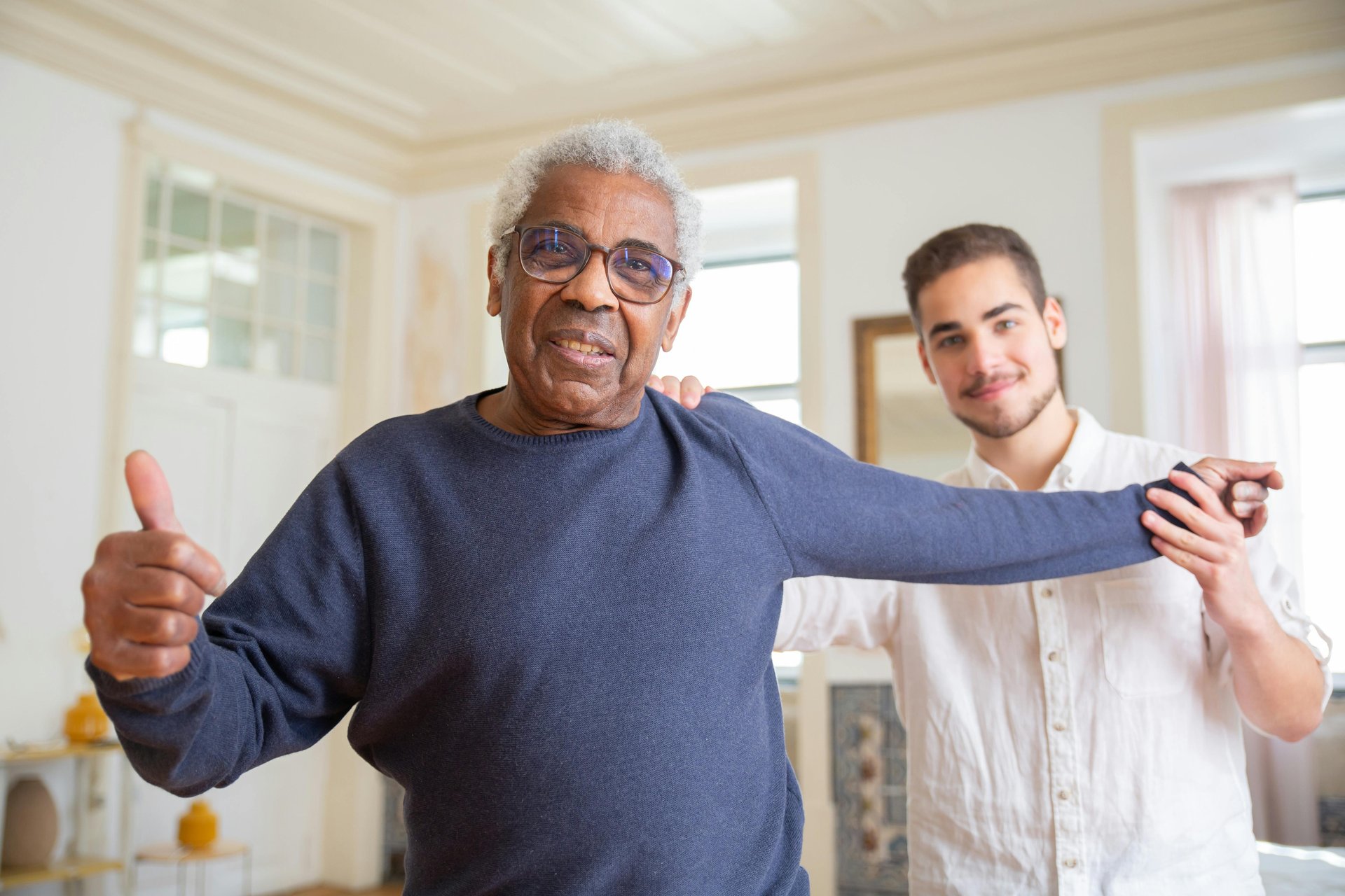 Elderly man smiling with caregiver in supportive home environment