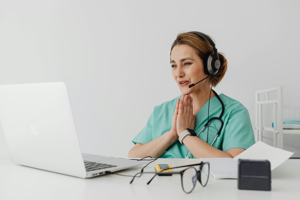 Female healthcare professional conducting online medical consultation wearing headphones and stethoscope