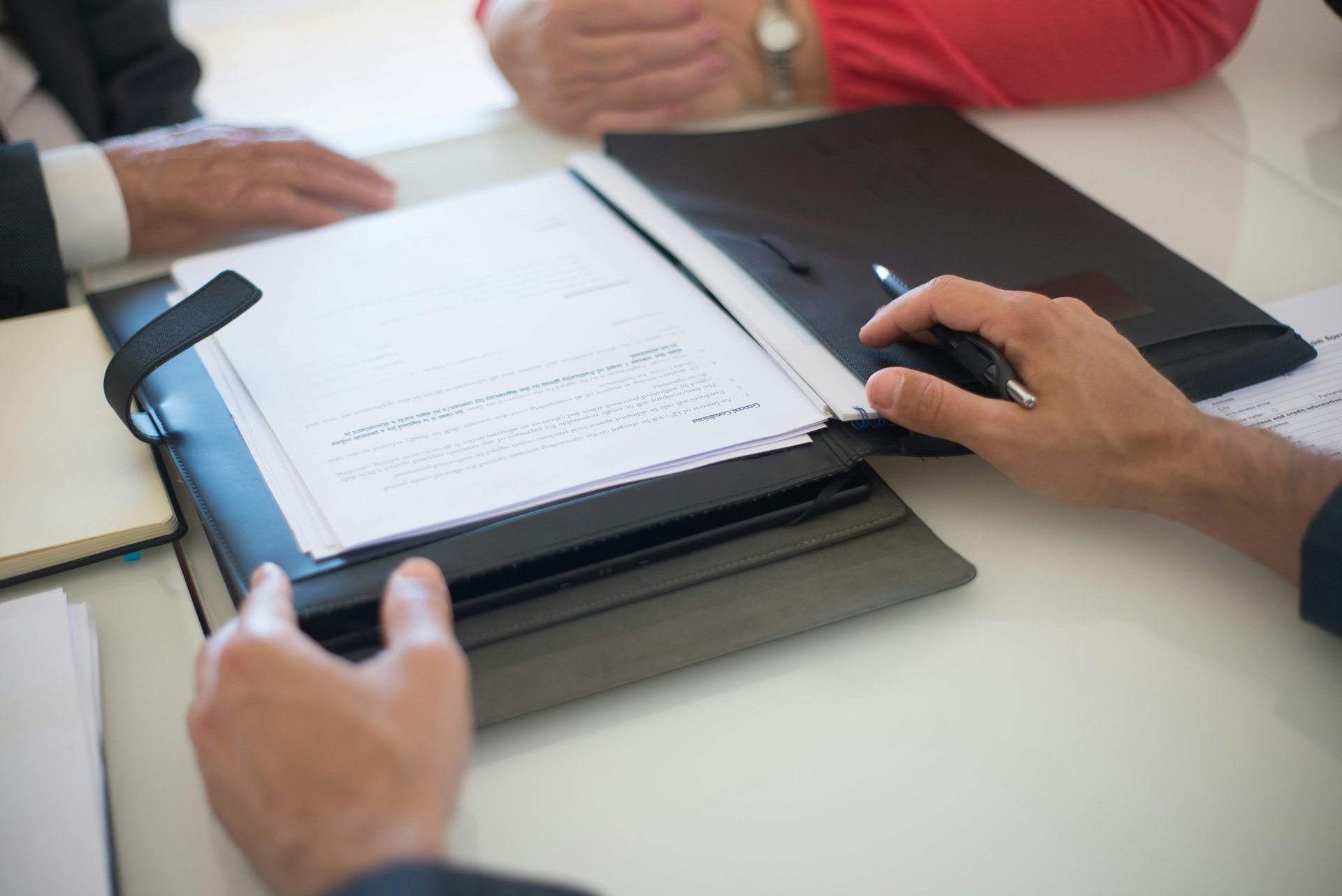 Two professionals discussing an NDIS business plan and contract documents at a meeting table